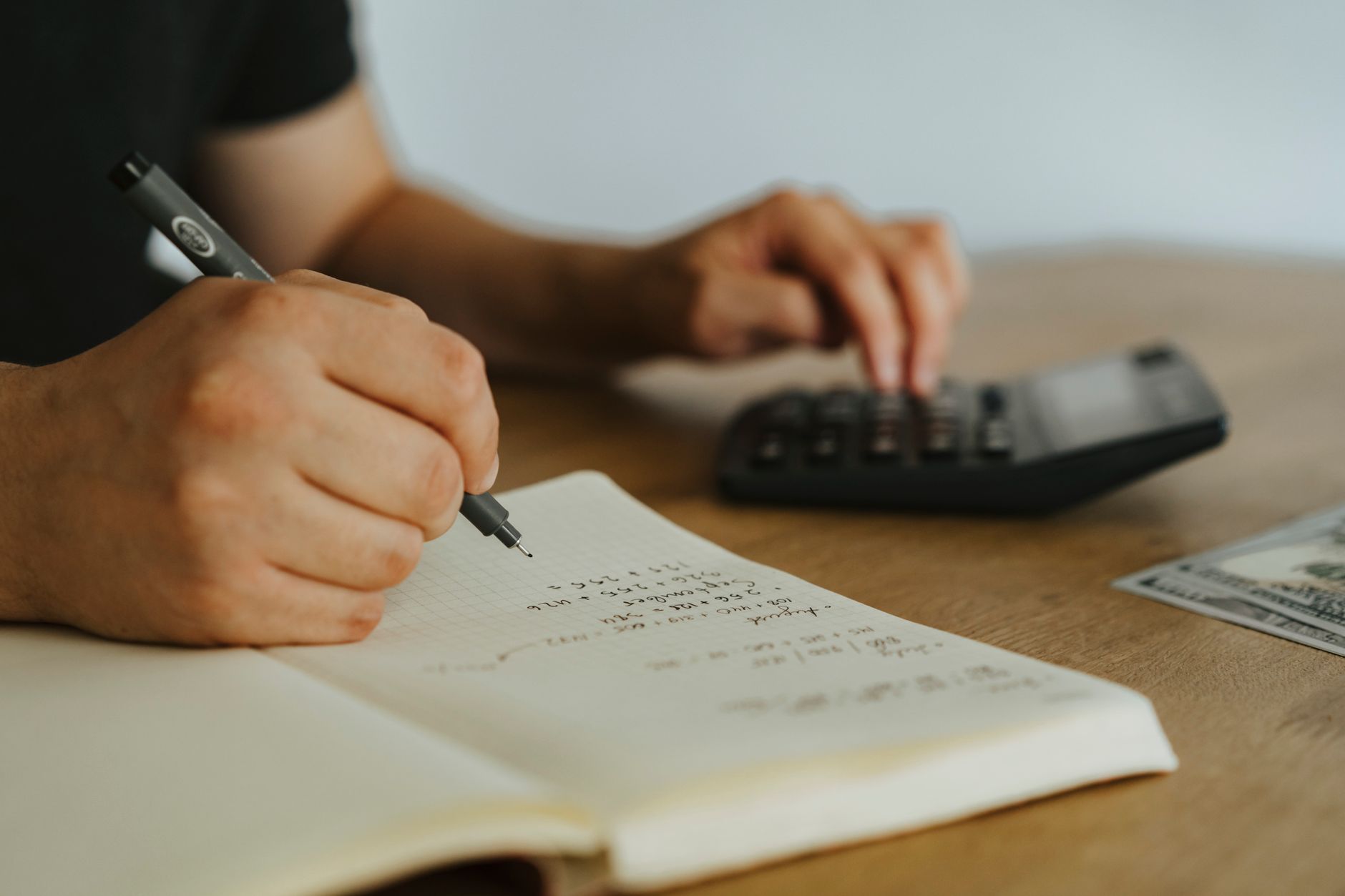 Pessoa fazendo contas com calculadora e caderno