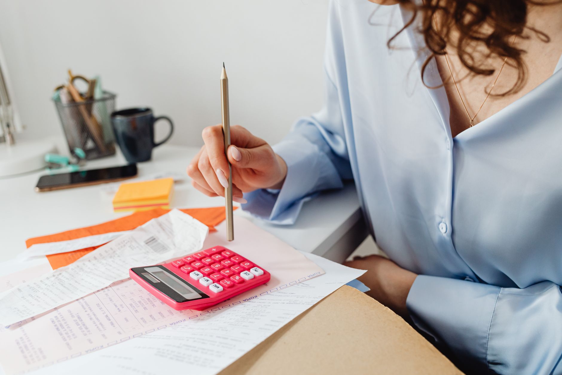 Mulher fazendo contas com calculadora e papéis