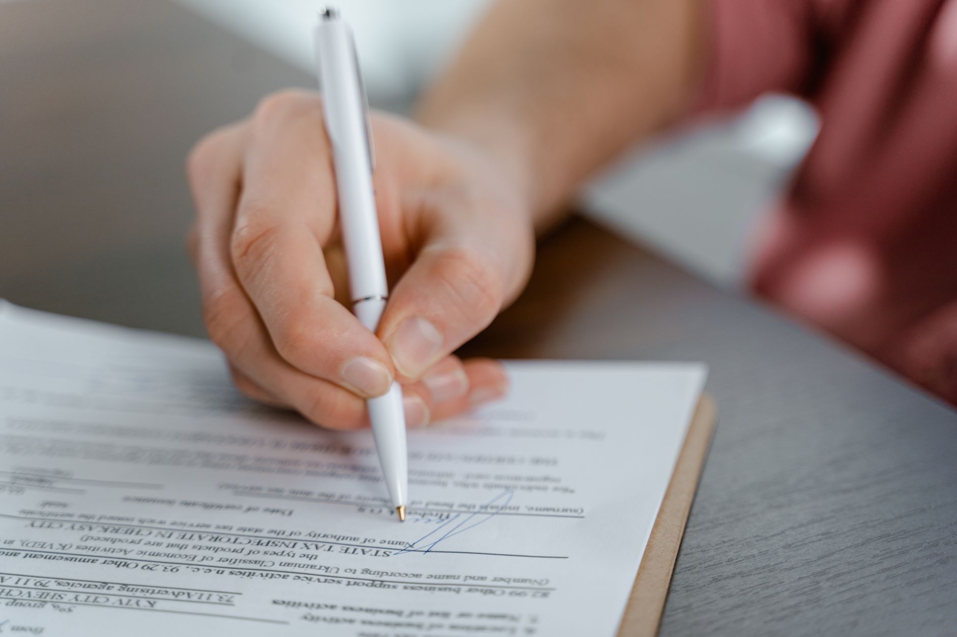 Mão assinando um documento