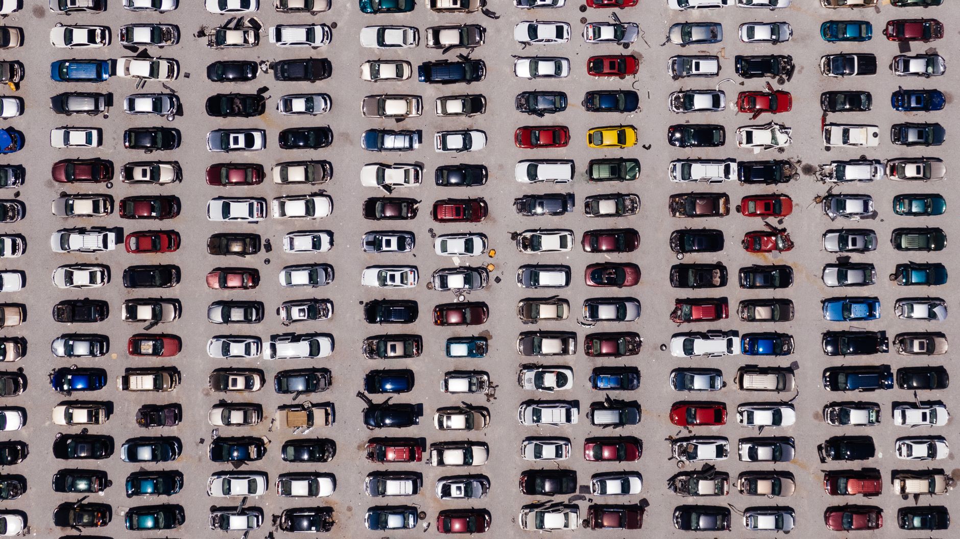 Vista aérea de um pátio com centenas de carros usados estacionados em fileiras