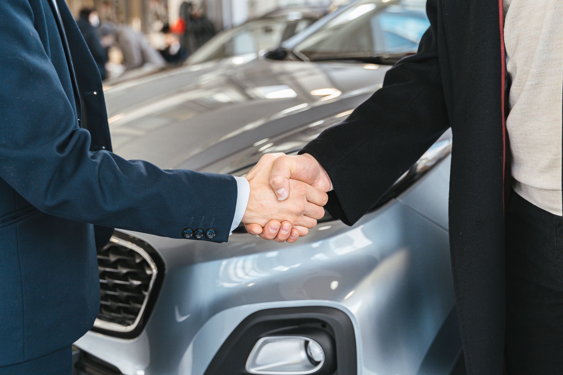 Aperto de mãos entre comprador e vendedor ao lado de um carro