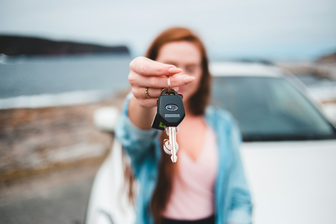 Mulher segurando a chave de um carro em frente ao veículo