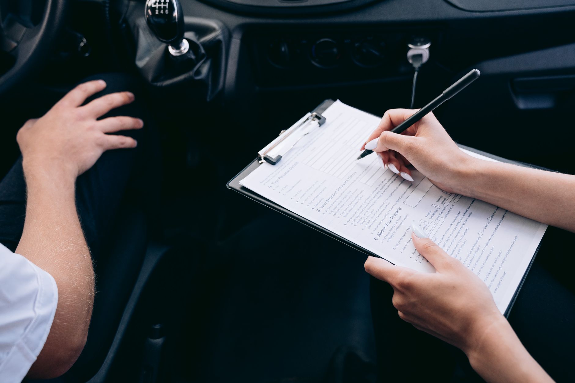 Pessoa com prancheta preenchendo documentos dentro de um carro