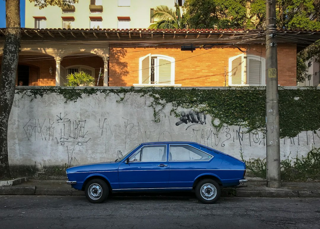 Carro azul antigo estacionado em uma rua em frente a um muro