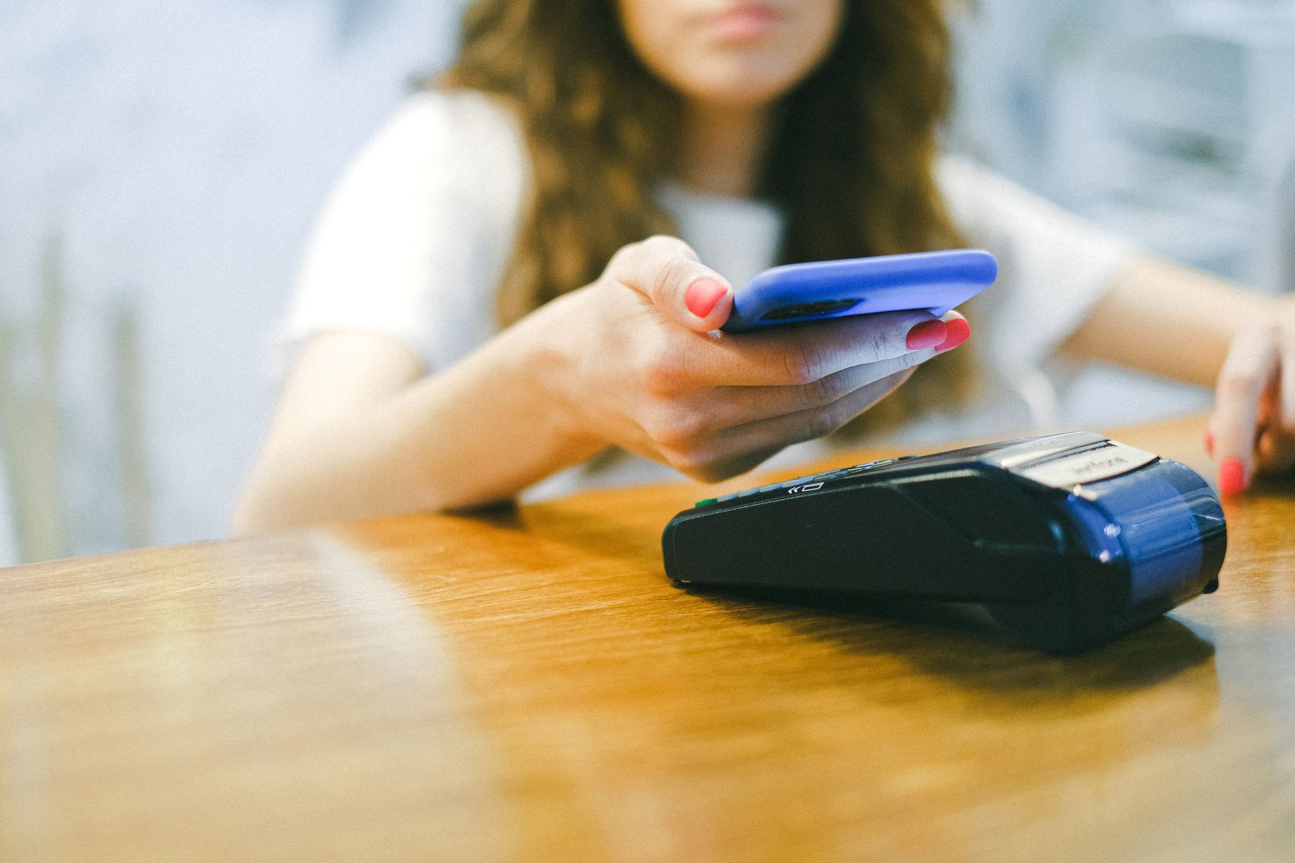 Pessoa pagando por aproximação com o celular em uma maquininha