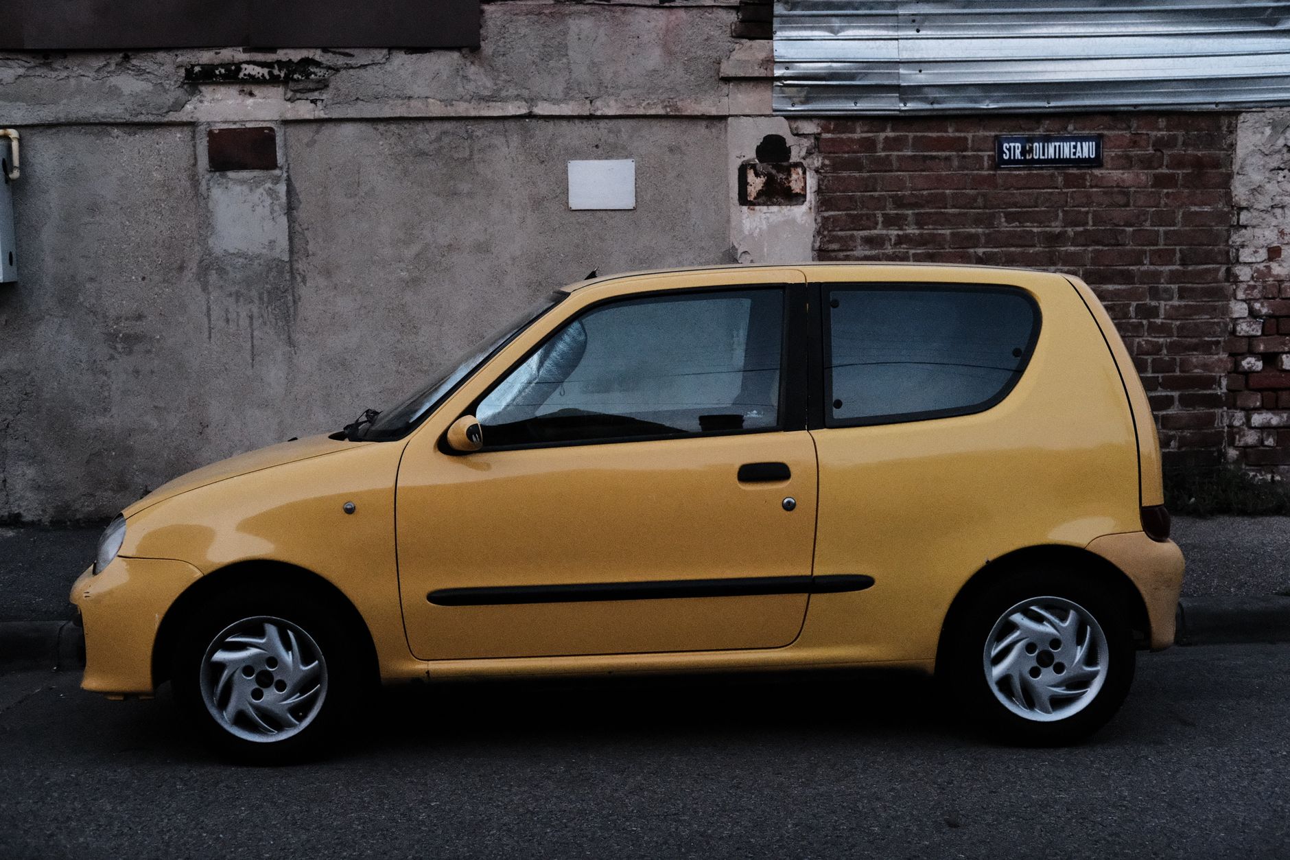 Carro compacto amarelo estacionado em uma rua