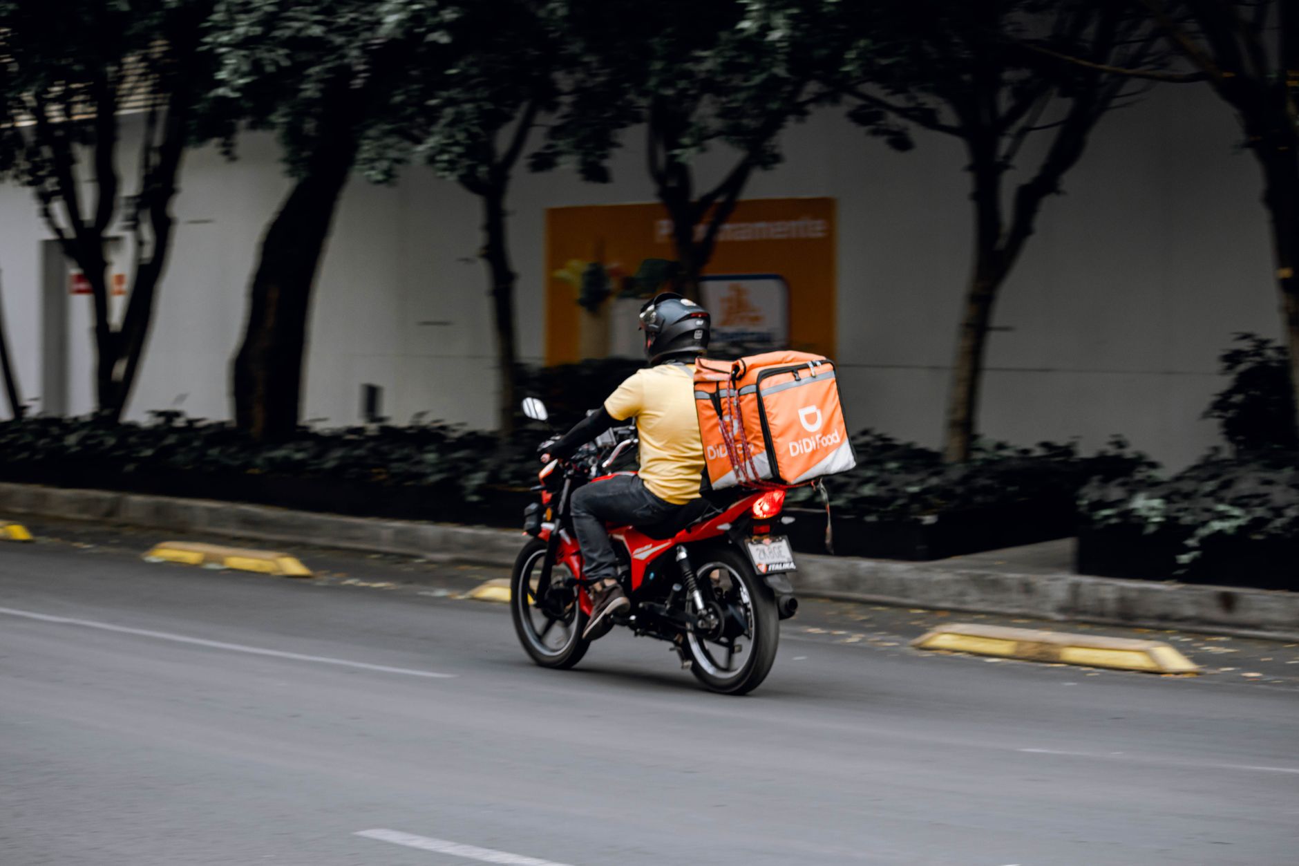 Motoboy com baú de entrega pilotando em uma avenida