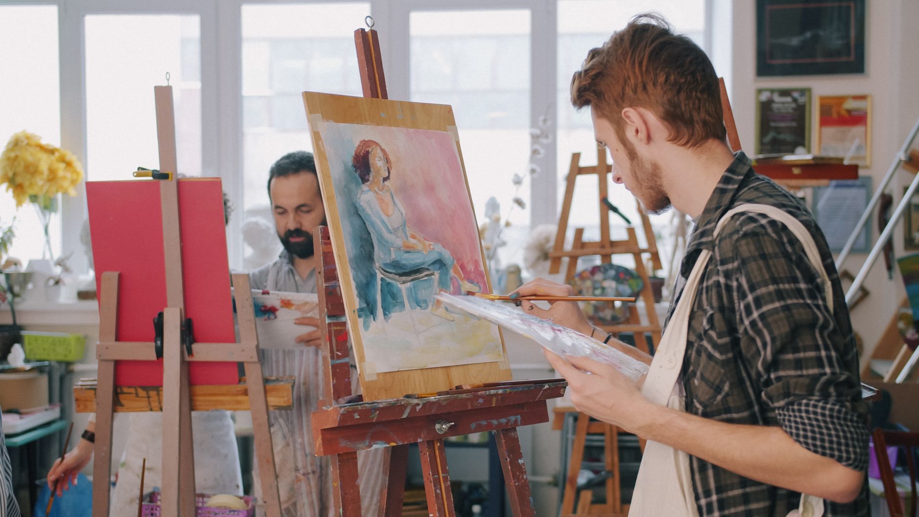 Alunos pintando em cavaletes durante uma oficina de arte