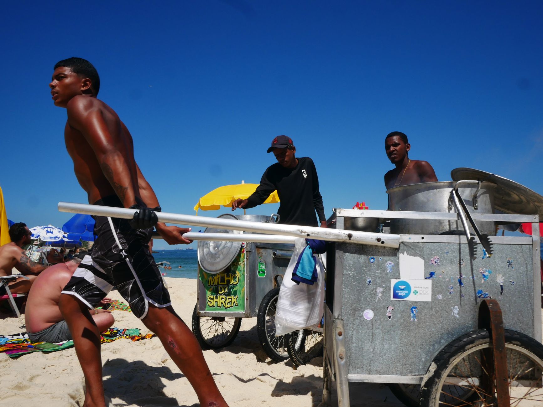 Vendedor ambulante empurrando carrinho na areia de uma praia