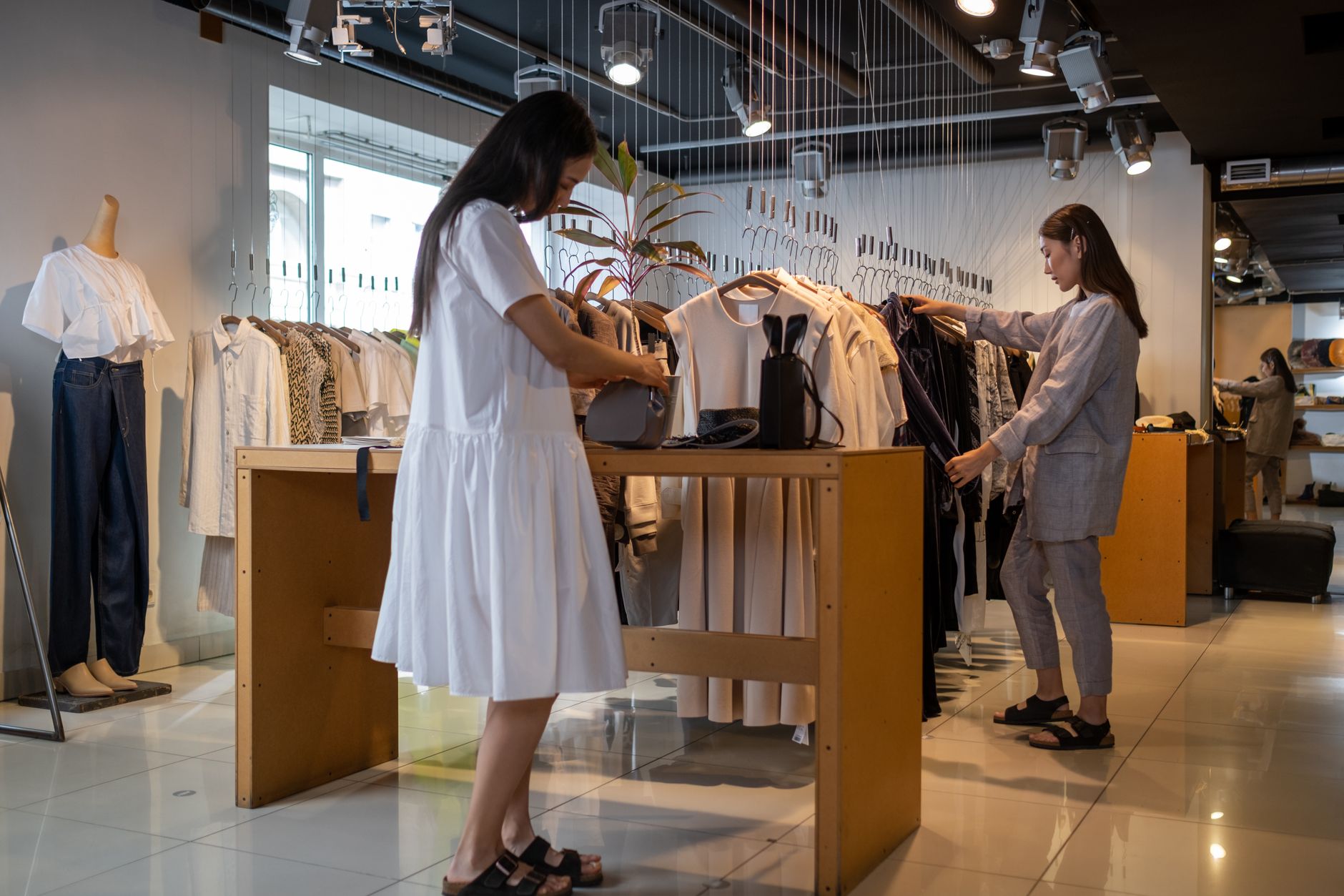 Cliente olhando peças em uma loja de roupas iluminada