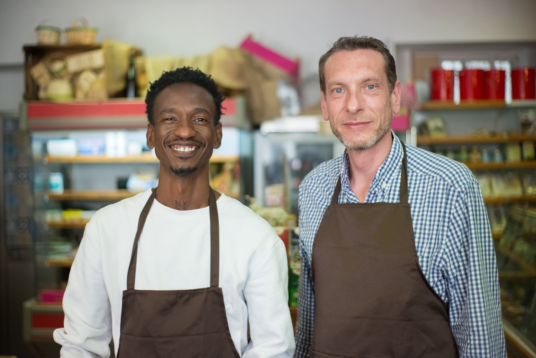Dois comerciantes sorrindo dentro de uma mercearia