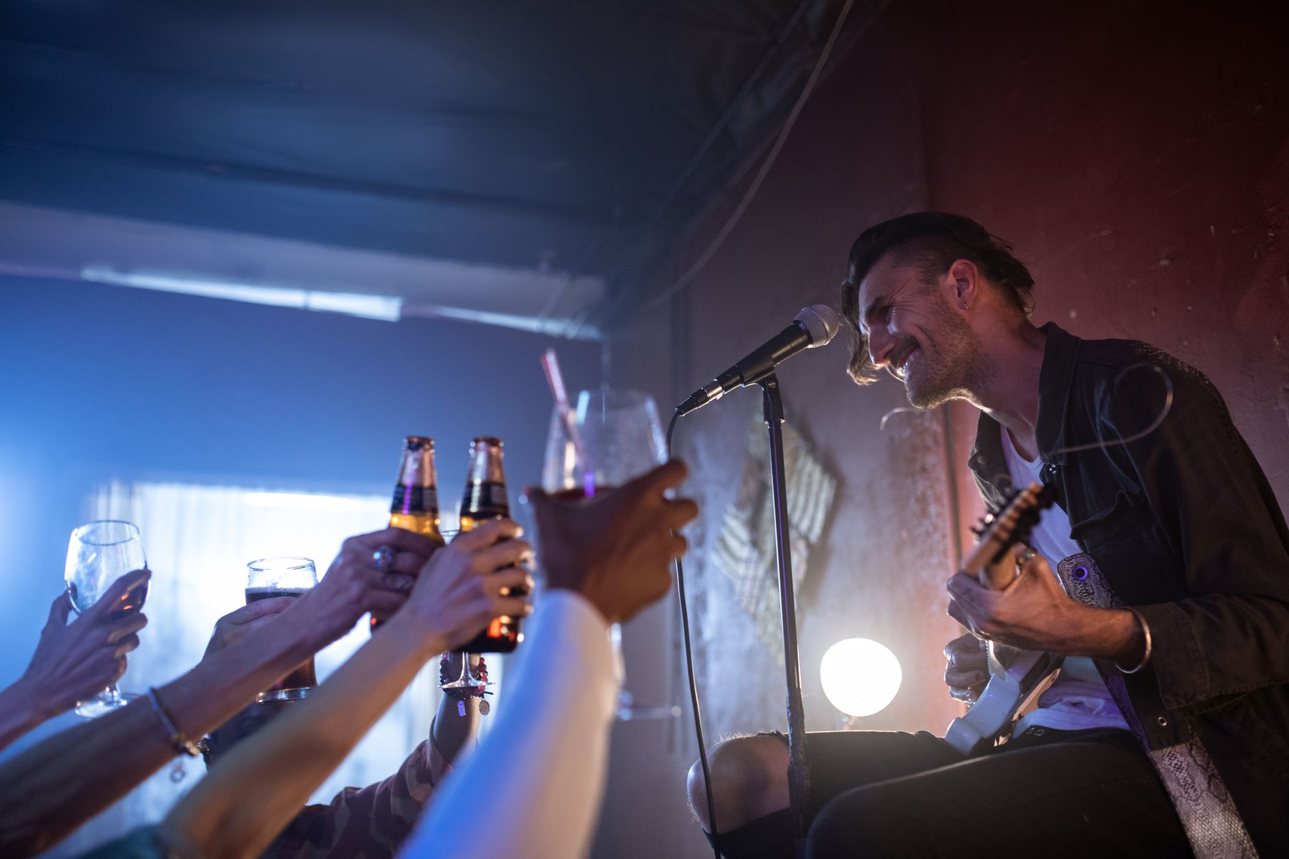 Público brindando com bebidas diante de um palco durante um show