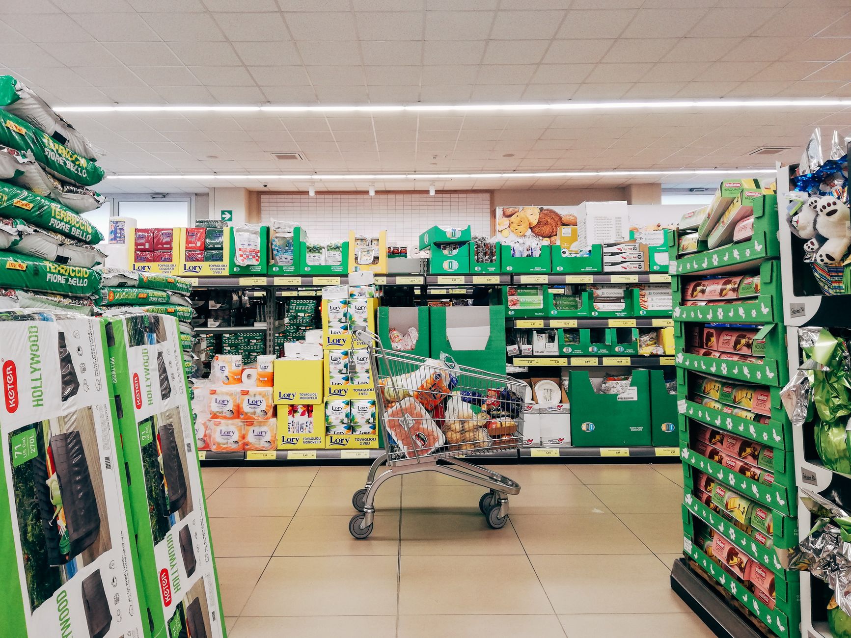 Corredor de supermercado com carrinho e prateleiras cheias