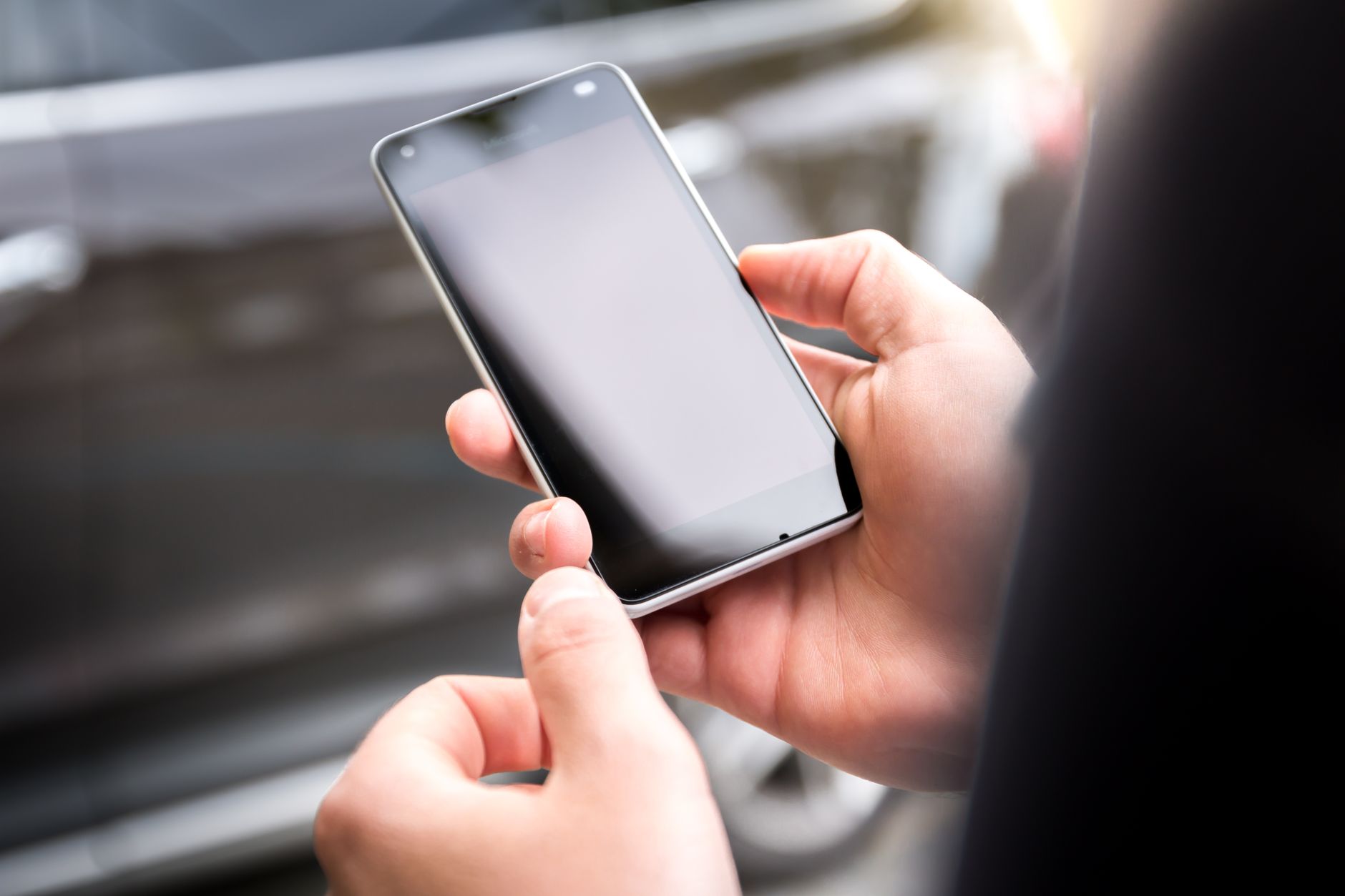 Mãos segurando um smartphone com a tela apagada