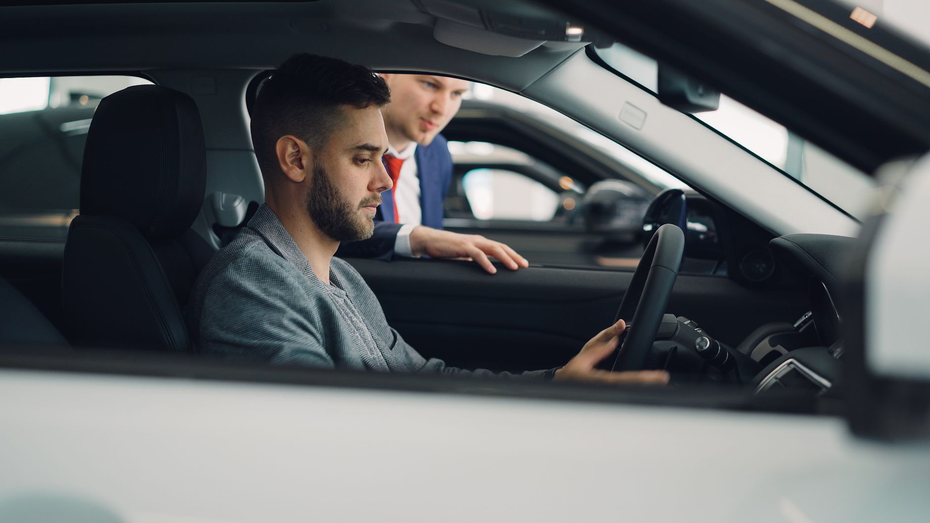 Homem sentado ao volante de um carro em uma concessionária