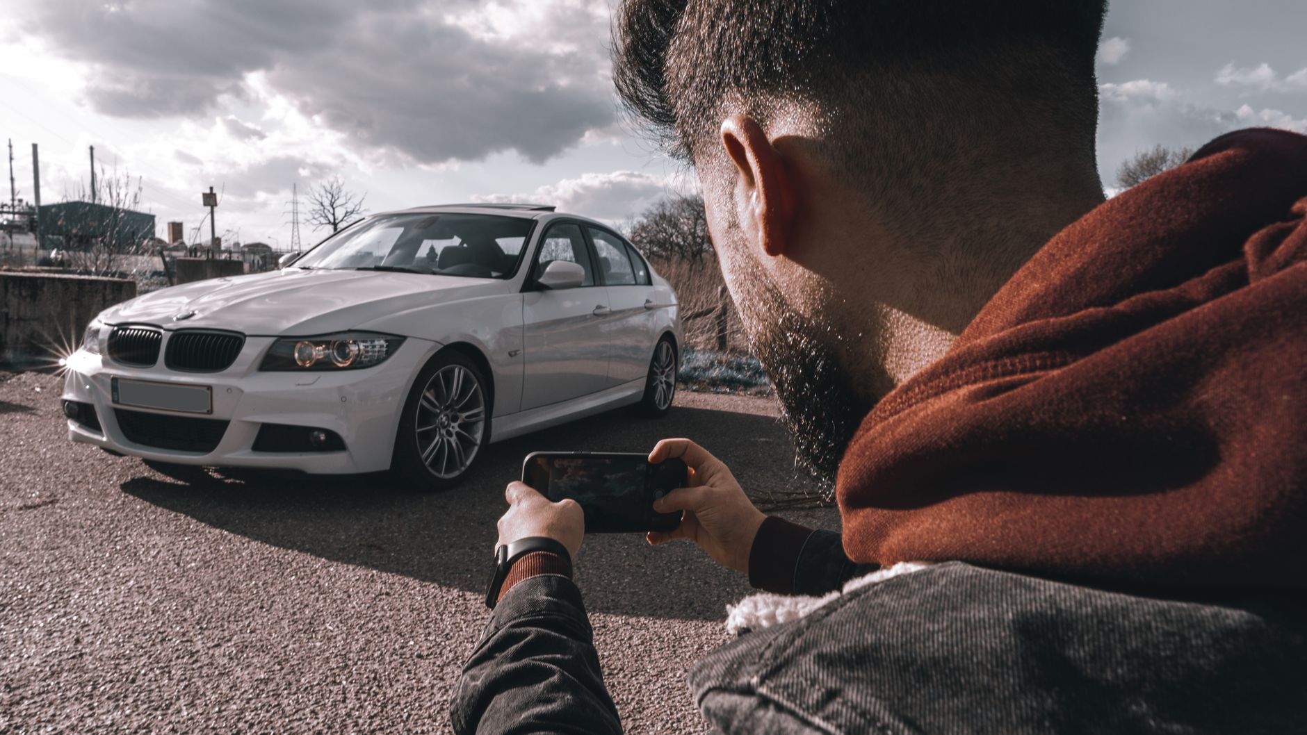 Homem fotografando um carro estacionado com o celular