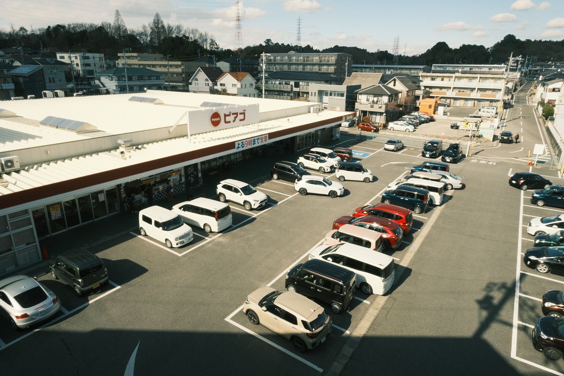 Estacionamento de loja com carros enfileirados ao sol
