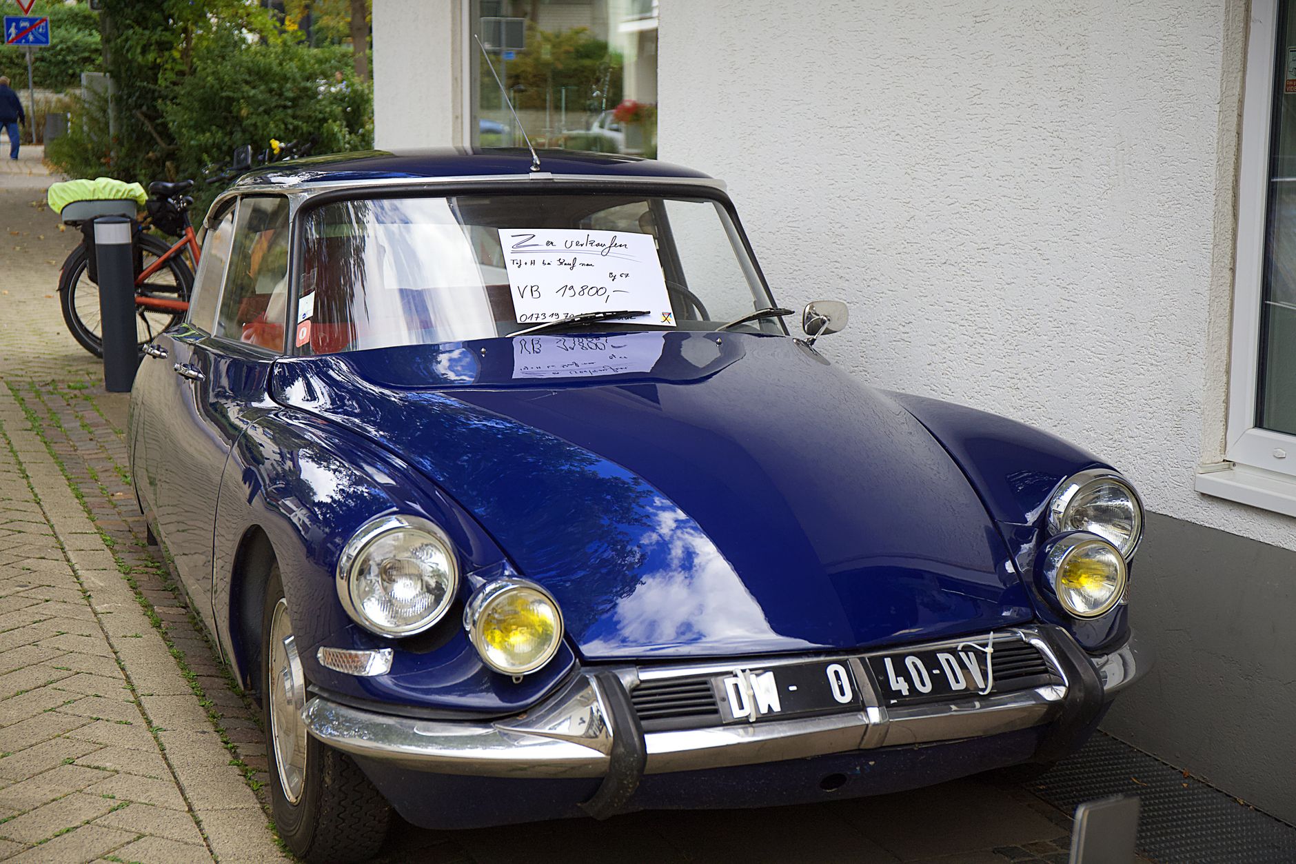Carro clássico azul estacionado com placa de venda