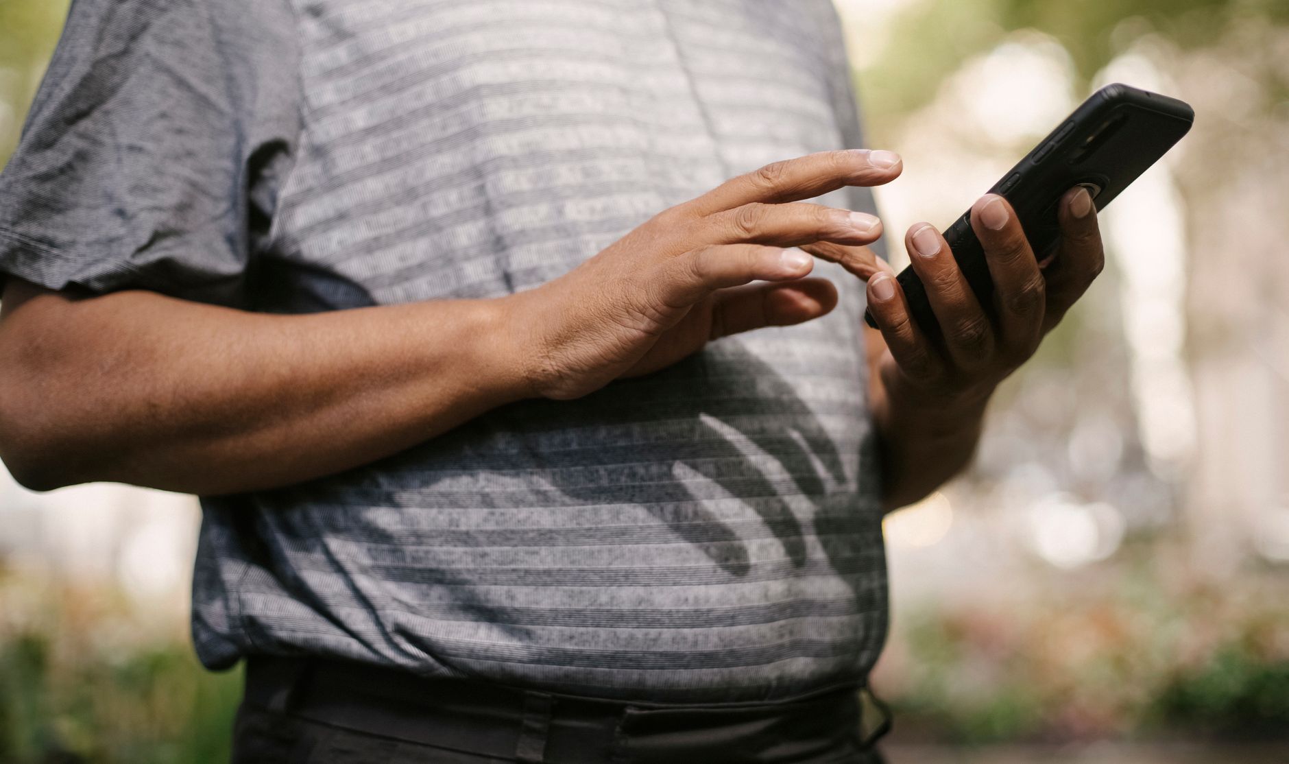 Homem segurando um celular na rua