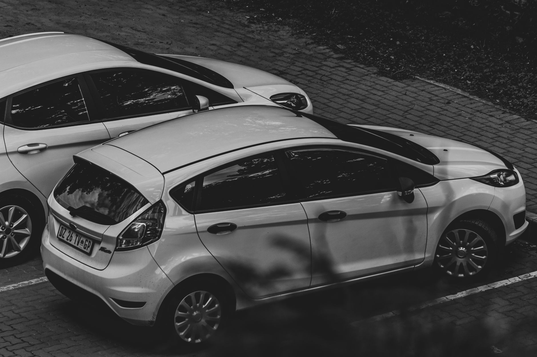 Carro branco estacionado em uma rua arborizada