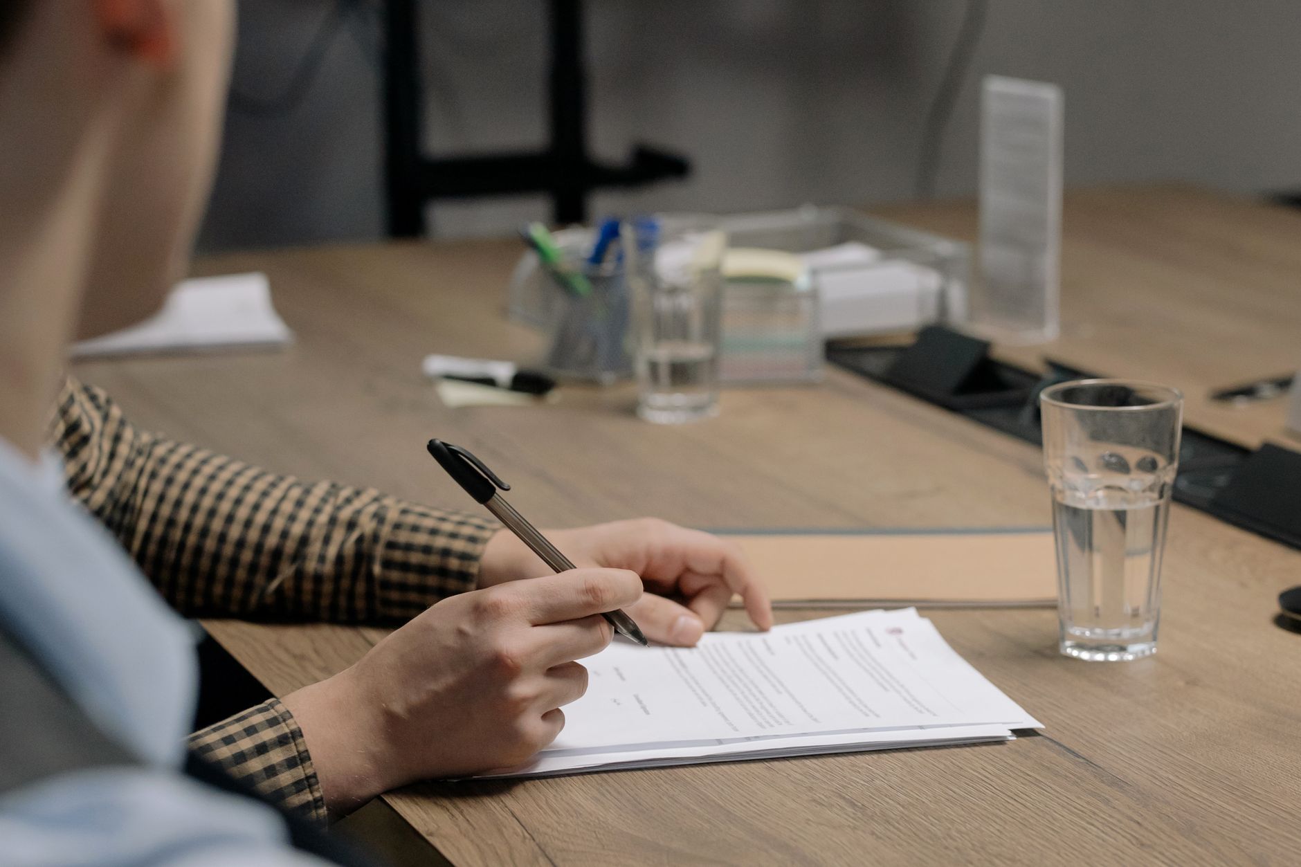 Pessoas analisando documentos em uma mesa com um copo d'água